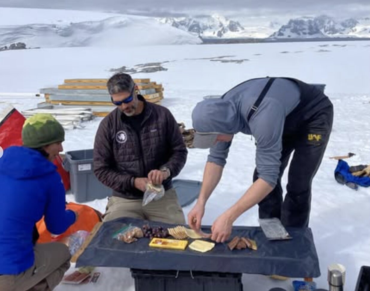 Field team members preparing snacks together outside on the Antarctic snow